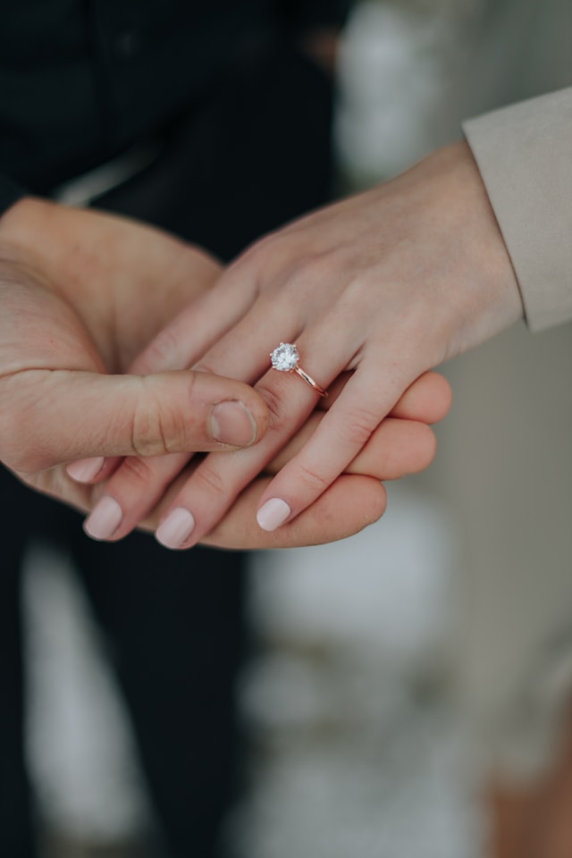 男性が女性の指に婚約指輪をはめるシーン