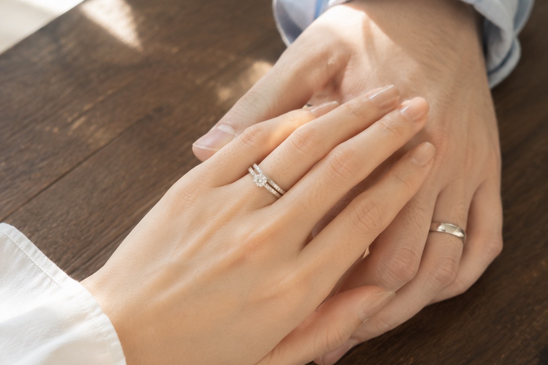 結婚指輪を左手の薬指につけたカップルの手